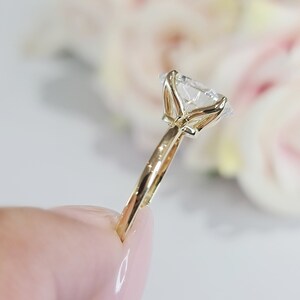 May include: A gold engagement ring with a large, clear, round diamond set in a four-prong setting. The ring has a simple band.