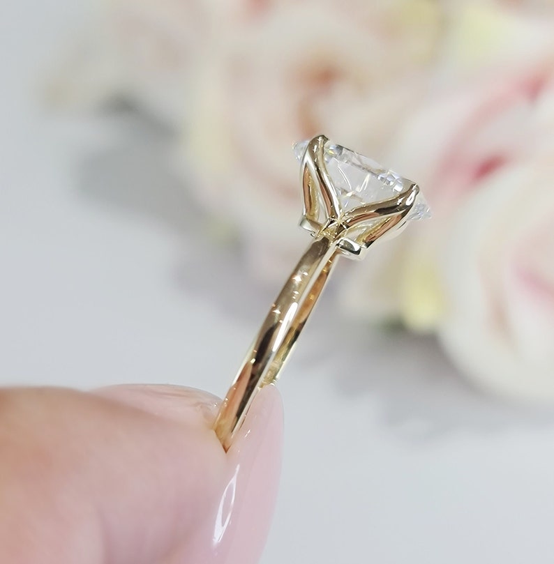 May include: A gold engagement ring with a large, clear, round diamond set in a four-prong setting. The ring has a simple band.