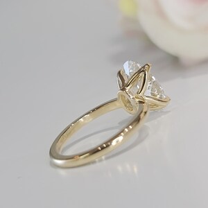 May include: A gold engagement ring with a large, clear, round diamond set in a prong setting.