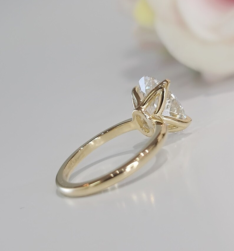 May include: A gold engagement ring with a large, clear, round diamond set in a prong setting.