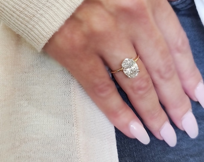 This unique two tone oval engagement ring features a 3 Carat Oval cut IGI certified CVD lab grown diamond set in a 4 prong hidden halo