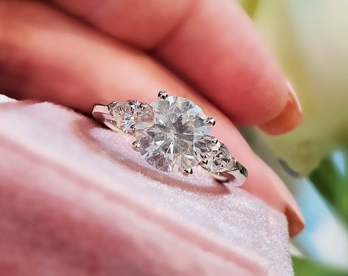 This Classic Three Stone Engagement Ring features a 2 carat Ideal round cut diamond and 0.50 carats teardrop side diamonds