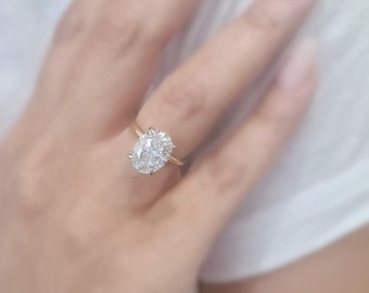 Może przedstawiać: Złoty pierścionek z dużym owalnym diamentem osadzonym w oprawie typu pavé.