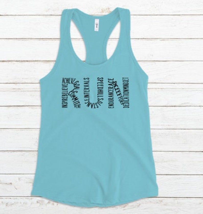 May include: A light blue tank top with the word "RUN" spelled out in black text. The letters are made up of words related to running, such as "achieve", "inspire", "believe", "commit", "goals", "speed", "hills", "endurance", "race", "effort", "dedication", and "mindset".