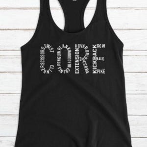 May include: Black racerback tank top with white text spelling "CORE" and surrounding exercise names like "Scissors", "Penguin", and "Kickback". The tank top has a scoop neck and a racerback design.