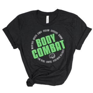 May include: Black t-shirt with a white circle graphic that says "BODY COMBAT" in green letters. The circle also has the text "MUAY THAI - KEFATE - GINGA - ESQUINA - COFELIAA - ECX - ONE TRIBE - UNITED - STAY WITH THE FIGHT" in white.