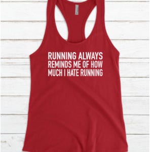 May include: A red racerback tank top with white text that reads, "RUNNING ALWAYS REMINDS ME OF HOW MUCH I HATE RUNNING." The tank top is made of a soft material and has a scoop neck and a racerback design.