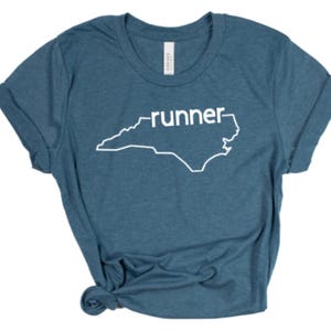 May include: A teal blue t-shirt with a white outline of the state of North Carolina and the word "runner" printed on it.