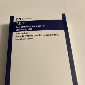 Puede incluir: Caja blanca con borde azul, etiquetada "T.E.D.™ Anti-Embolism Stockings for Continuing Care" y "Bas anti-embolie pour les soins en continu".