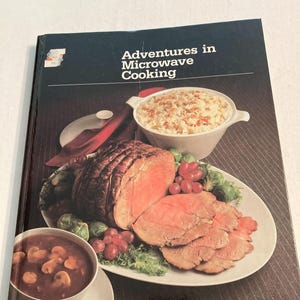 May include: A vintage cookbook titled "Adventures in Microwave Cooking" by Montgomery Ward. The cover features a photo of a roasted meat, a bowl of rice, and a bowl of mushroom gravy.