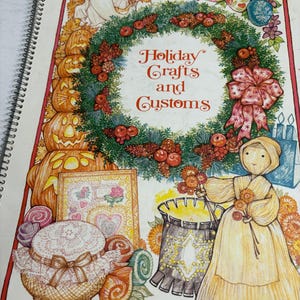 May include: A vintage book cover with the title "Holiday Crafts and Customs" in red script. The cover features illustrations of pumpkins, a ghost, a wreath, and a woman in a yellow dress. Other illustrations include a jar, candies, and a framed picture.