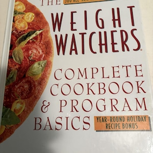 May include: A hardback cookbook titled Weight Watchers Complete Cookbook & Program Basics with a white cover featuring a large image of a tomato and basil pizza on the left side and red text detailing 500 all-new irresistible recipes.