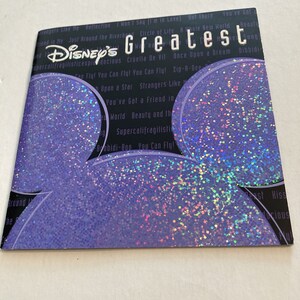 May include: A purple and blue glittery background with a black Mickey Mouse silhouette. The text "Disney's Greatest" is printed in white letters on the background.