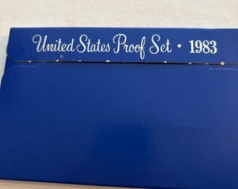 Peut inclure: Une enveloppe bleue avec le texte "United States Proof Set • 1983" en écriture blanche. L'enveloppe est d'un bleu profond et semble être en carton. Le texte est centré et en écriture cursive.