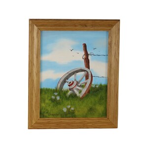 Puede incluir: Una pintura enmarcada de una rueda de carro blanca que yace en un campo de hierba con un poste de cerca de madera y alambre de púas en el fondo. El cielo es azul con nubes blancas y hay pájaros volando en el cielo. La pintura está firmada "Walt Breaux".