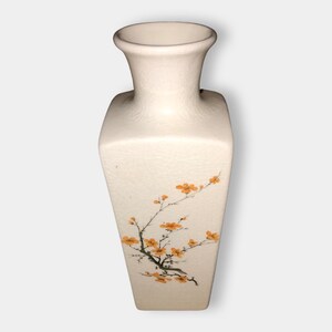 May include: White ceramic vase with a textured surface and a floral design featuring a branch with orange blossoms.