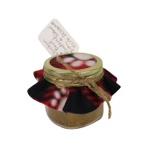 May include: A small glass jar with a gold lid and a red and black plaid fabric cover. The jar contains a brown spice blend. A white label attached to the jar reads "Chicken,  Powdered +  Bone Broth Help  Digestive".
