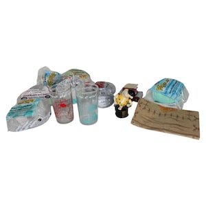 May include: A collection of vintage Flintstones themed items including a set of four clear glass tumblers with colorful cartoon graphics, a small plastic figurine of Fred Flintstone, and several plastic bags with the Flintstones logo.
