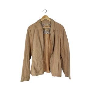 May include: A tan suede jacket with a zipper closure and a floral patterned lining. The jacket has a collar and long sleeves.
