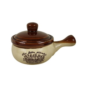 May include: A brown and beige ceramic soup pot with a lid and handle. The pot has the words "Live Better Naturally" and a wheat graphic. The lid and handle are a darker brown than the pot's body.