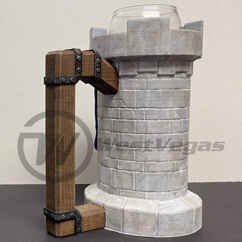 Puede incluir: Una taza de cer&aacute;mica blanca con forma de castillo con un asa de madera marr&oacute;n. La taza tiene una textura de piedra y una bandera azul y blanca colgando del asa.