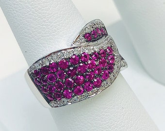 May include: A white gold ring with a wave-like design set with pink sapphires and white diamonds.