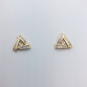May include: A pair of gold earrings with a triangular design set with small, clear baguette-shaped diamonds.
