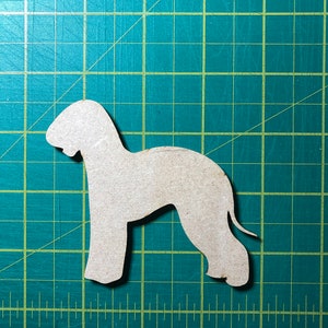 May include: A cutout of a beige dog silhouette on a green cutting mat.