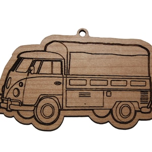 May include: A wooden cutout of a vintage camper van with a flatbed truck bed. The van is outlined in black and has a simple design.