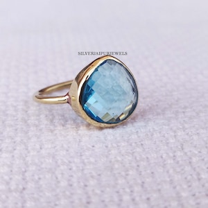 May include: A gold ring with a large, teardrop-shaped blue gemstone.