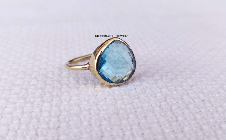 May include: A gold ring with a large, teardrop-shaped blue gemstone.