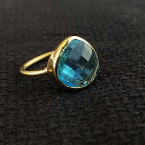 May include: A gold ring with a large, teardrop-shaped blue gemstone.