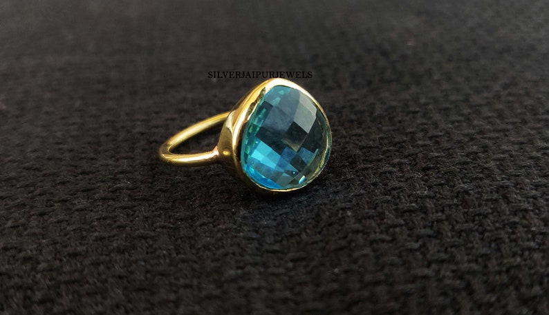 May include: A gold ring with a large, teardrop-shaped blue gemstone.