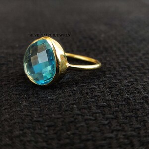 May include: A gold ring with a large, round, light blue gemstone. The gemstone has a faceted cut.