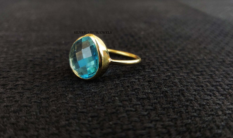 May include: A gold ring with a large, round, light blue gemstone. The gemstone has a faceted cut.