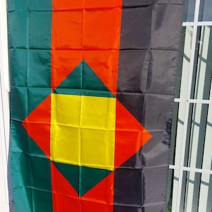 May include: A green, red, yellow, and black flag with a diamond shape in the center. The diamond is made up of smaller squares of green, yellow, and red.