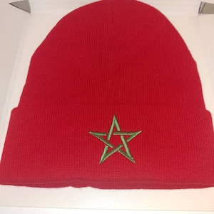 May include: Red knit beanie with a green embroidered star.