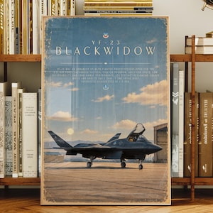 Pode incluir: Um cartaz vertical apresentando um caça furtivo YF-23 Black Widow em uma pista sob um céu nublado. O texto diz YF-23 BLACKWIDOW seguido por um parágrafo descritivo sobre o desenvolvimento, a furtividade e o desempenho da aeronave.