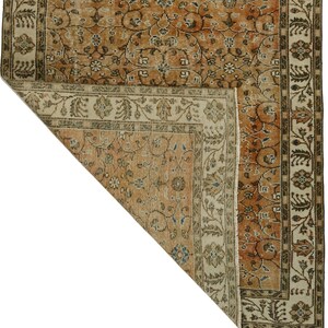 May include: A vintage rug with a floral pattern in shades of brown, beige, and cream. The rug has a border with a repeating design.