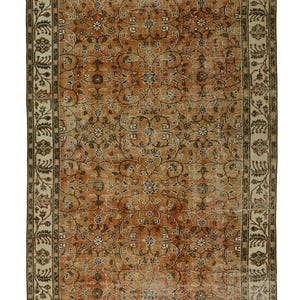 May include: A vintage rug with a floral pattern in shades of brown, beige, and cream. The rug has a border with a repeating design.