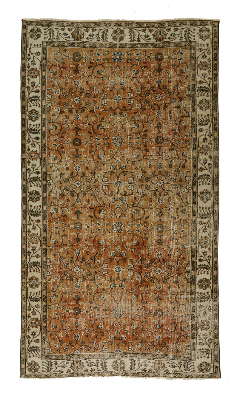 May include: A vintage rug with a floral pattern in shades of brown, beige, and cream. The rug has a border with a repeating design.