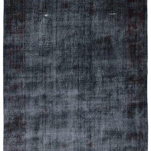 Puede incluir: Una alfombra de estilo vintage con un esquema de color azul descolorido y burdeos. La alfombra tiene un aspecto desgastado y un patrón sutil.