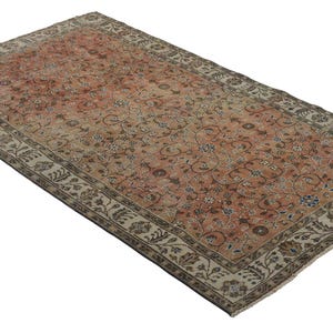 May include: A vintage rug with a floral pattern in shades of pink, beige, and brown. The rug has a cream-colored border with a floral design.