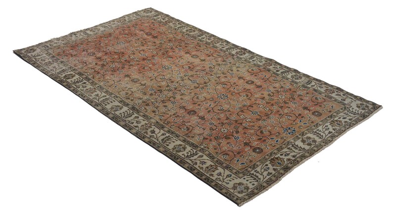 May include: A vintage rug with a floral pattern in shades of pink, beige, and brown. The rug has a cream-colored border with a floral design.