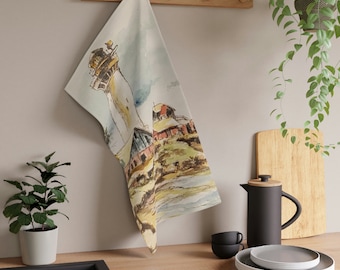 May include: A watercolor painting of a lighthouse on a cliff with a small building in the foreground. The painting is on a white kitchen towel.