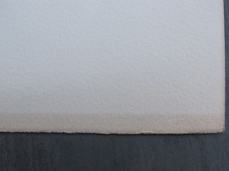 Pode incluir: Close-up da borda de uma folha de papel branca com uma superf&iacute;cie ligeiramente texturizada. O papel est&aacute; ligeiramente descolorido ao longo da borda.