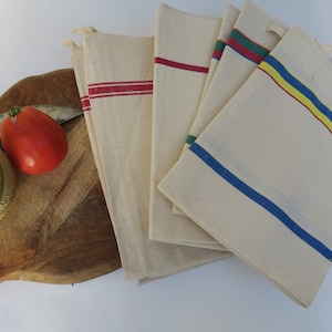 Puede incluir: Conjunto de seis toallas de cocina blancas con rayas de colores. Las toallas tienen rayas rojas, azules, amarillas y verdes.