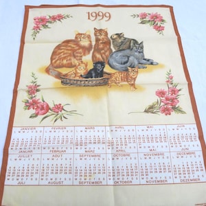 Puede incluir: Un calendario vintage de 1999 con un grupo de gatos en una cesta. El calendario está impreso en una tela de color crema con un borde marrón. Los meses están listados en francés y los días de la semana están abreviados en francés.