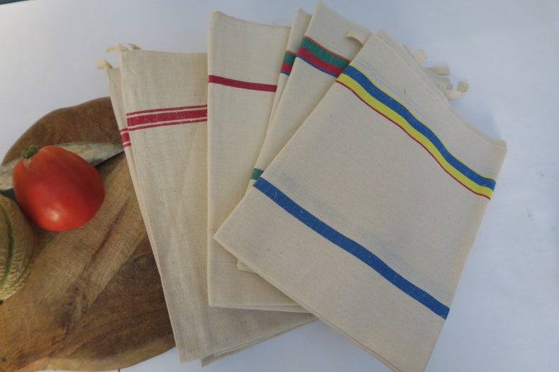 Puede incluir: Conjunto de cinco toallas de cocina blancas con rayas de colores. Las toallas tienen rayas rojas, azules, amarillas y verdes.