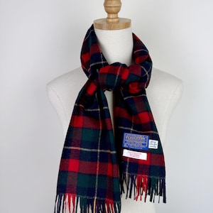 Pode incluir: Cachecol xadrez vermelho, verde, azul marinho e dourado com franjas. O cachecol é exibido em um manequim. Uma etiqueta azul e branca com o nome da marca é visível.